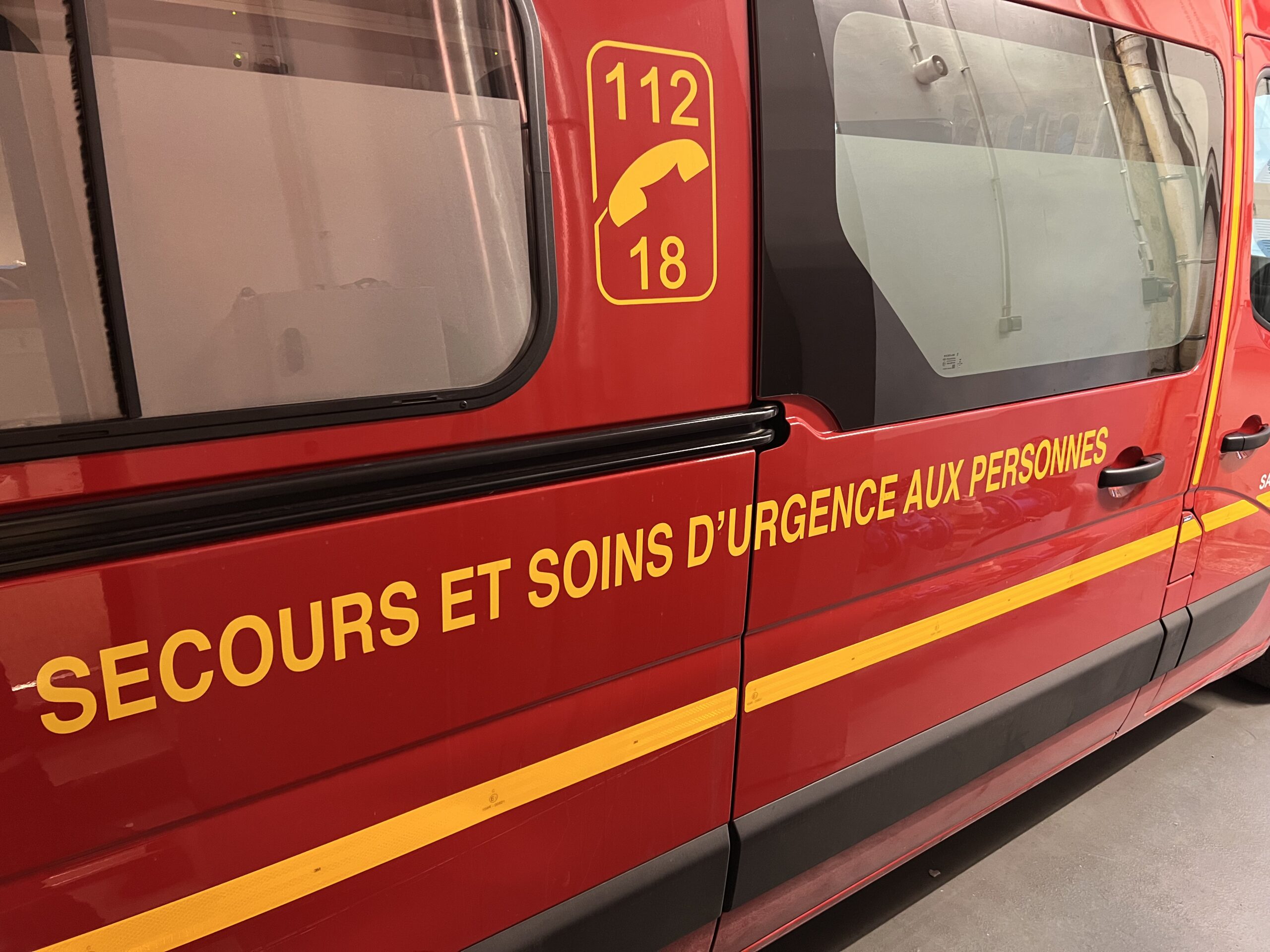 Un véhicule d’urgence rouge avec le texte jaune « SECOURS ET SOINS D’URGENCE AUX PERSONNES » et les numéros de téléphone d’urgence 112 et 18 affichés sur le côté. Devenir Pompier